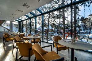 兹拉蒂博尔Mona Plaza Zlatibor的餐厅设有桌椅和大窗户。
