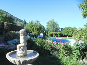 IznallozHostal El 402的花园内的石头喷泉,花园内设有游泳池