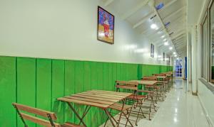 海得拉巴Treebo Trend Blue Dawn Gachibowli的绿墙中的一排桌椅