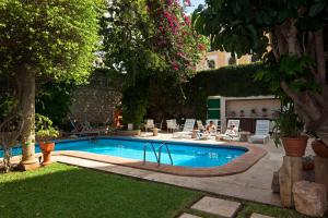 梅里达Casa del Balam Merida的院子里的游泳池,周围的人坐在游泳池周围