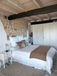 UdiasLa buganvilla en Udías的卧室配有一张白色的大床和石墙