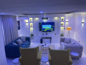阿布贾Morak Homes - Luxury 4 bed home with PS5, 24hrs electricity, Super fast Wifi, Snooker, Games room - in a secured estate的客厅配有两张沙发和一台电视机