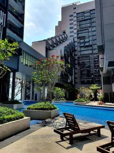 马六甲BotakCuteHomestay@Imperio Residence的一座带长凳的建筑和一座建筑中的游泳池