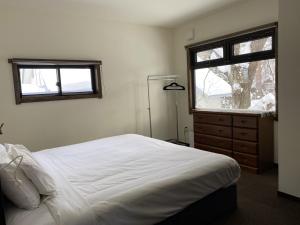 白马村黄色小屋旅馆的卧室配有白色的床和窗户。