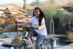利雅德Najdarah Resort的一名妇女在花园里骑着自行车