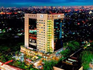雅加达Hotel KIMAYA Slipi Jakarta By HARRIS的一座高大的建筑,晚上在城市里亮着灯