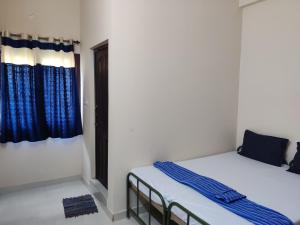 哥印拜陀Sundaram Rooms的配有蓝色窗帘的客房内的两张床