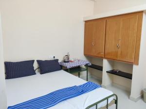 哥印拜陀Sundaram Rooms的一间卧室配有两张床、一个橱柜和一张桌子