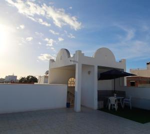 哈曼苏斯Nice Holiday Apartment Hammam Sousse的白色的建筑,配有桌子和雨伞