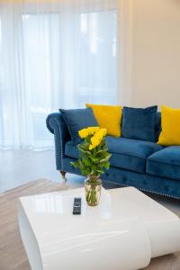 考纳斯Luxurious Blue&Yellow Apartment in Kaunas Center的客厅设有蓝色的沙发和一个黄色花瓶