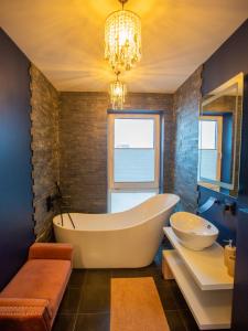 考纳斯Luxurious Blue&Yellow Apartment in Kaunas Center的带浴缸、水槽和吊灯的浴室