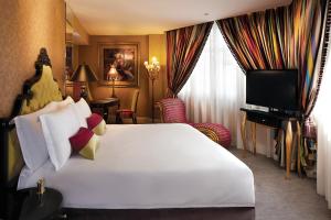 新加坡The Scarlet Singapore的酒店客房设有一张白色大床和一台电视。