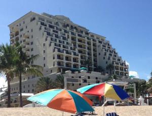 劳德代尔堡The Atlantic Hotel & Spa Condo的大型建筑前的海滩上两把遮阳伞