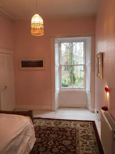 斯温顿Swinton Manse & Gardens的一间卧室设有窗户、一张床和一个吊灯。