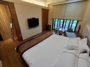 头城Ciao Home的卧室配有一张白色大床和电视。