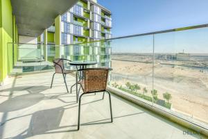 迪拜Alluring 1BR at The Pulse Blvd C3 Dubai South by Deluxe Holiday Homes的阳台配有桌椅,享有海滩美景。