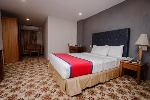 达卡Hotel The Enchanted的酒店客房设有一张大床和一张书桌。