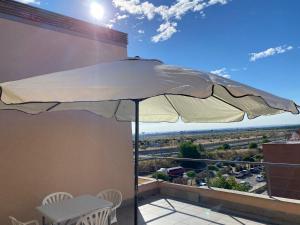阿尔考空Apartamento de 1 dormitorio, Ático 4PAX的阳台上的白色遮阳伞,配有桌椅