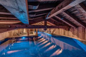 瓦勒迪泽尔HOTEL LE VAL D'ISERE的一个带木制天花板和蓝色海水的室内游泳池