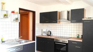 温蒂加斯顿Ferienwohnung Brandstatter的厨房配有黑色橱柜和水槽