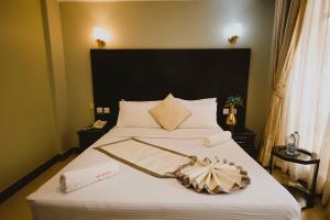 莫希Panone Hotels - King'ori Kilimanjaro Airport的卧室配有一张大白色的床和大床头板