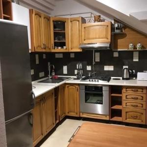 利沃夫Затишна квартира в спальному районі的厨房配有木制橱柜和不锈钢冰箱。