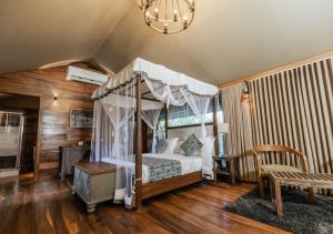雅拉Tribe Yala - Luxury Camping的一间卧室设有一张天蓬床和木地板。