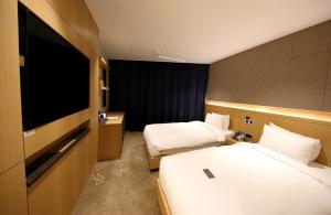 束草市Sea Cruise Hotel的酒店客房设有两张床和一台平面电视。