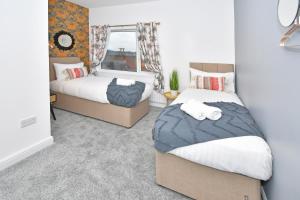 特伦特河畔斯托克A Cosy and Modern Mid-Terraced Retreat in Stoke!的一间卧室设有两张床和窗户。