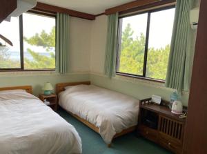 沼津遙かな亭的一间卧室设有两张床和两个窗户。