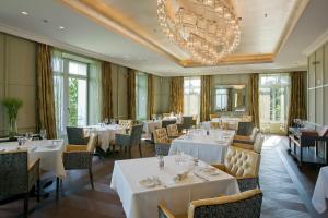 恩内特布尔根洪恩格别墅酒店的餐厅配有白色的桌椅和吊灯