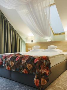 比亚韦斯托克Gościniec Folwark Nadawki的一间卧室配有一张带花卉图案的毯子的大床