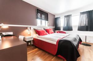 MelandsjøenDolmsundet Hotell Hitra的一间卧室配有一张带红色枕头的床和一张书桌