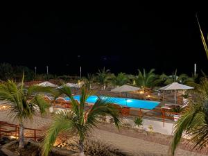 卡诺阿斯德蓬萨尔El Samay Hotel Boutique的游泳池在晚上配有遮阳伞和椅子,并种植了棕榈树