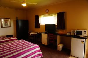马瑟尔布鲁克Muswellbrook Northside Bed & Breakfast的一间卧室配有一张床和一张带微波炉的书桌