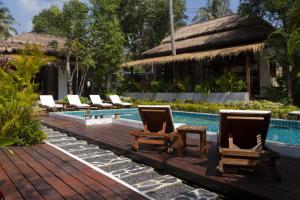 西塔努Amaya Boutique Resort的度假村旁的游泳池配有躺椅和桌子