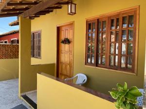 布希奥斯CASA BUZIOS PRAIA RASA的黄色的房子,设有木门和窗户