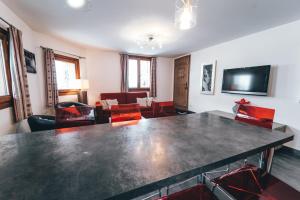 蒂涅Appartement Orion by ExplorHome的客厅配有大桌子和红色椅子