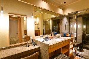 龟冈京汤之花翠泉日式旅馆的一间带水槽和大镜子的浴室