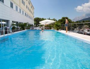 马卡尔斯卡米拉马尔公寓式酒店的站在一个蓝色的大游泳池旁的人