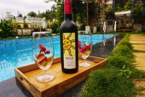 乌提La Niebla Farm Resort的木托盘上放有一瓶葡萄酒和两杯酒杯