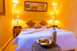 马拉喀什利亚德洛乌亚酒店的一间卧室,配有一张床上的床铺,桌上放着一碗水果