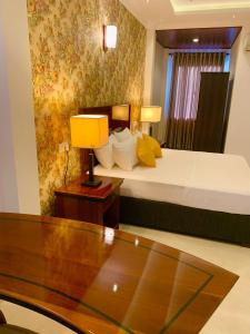Ambagahagedararuwanara royal majestry的酒店客房配有一张床和一张带台灯的桌子