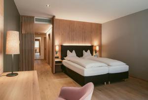 布鲁登茨巴拉兹阿尔卑斯山特拉布Spa高尔夫酒店的一间卧室配有一张大床和一张粉红色的椅子