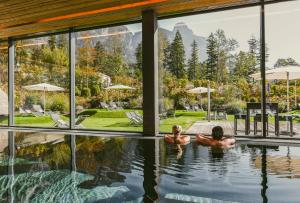布鲁登茨巴拉兹阿尔卑斯山特拉布Spa高尔夫酒店的两人在房子的游泳池游泳