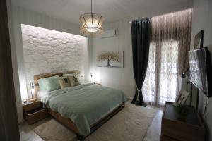 拉里萨LA Larissa Luxury Apartments Peneus的一间卧室设有一张床和一个大窗户