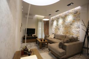 拉里萨LA Larissa Luxury Apartments Peneus的带沙发和石墙的客厅