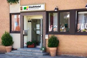 巴特法灵博斯特尔StadtHotel Bad Fallingbostel的建筑前有盆栽植物的商店