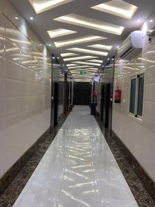 利雅德Elite Furnished Units的走廊设有白色的墙壁和带灯的天花板