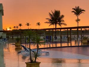 阿拉亚尔-杜卡布Golden Lake Arraial do Cabo Resort的日落时分带椅子和棕榈树的游泳池